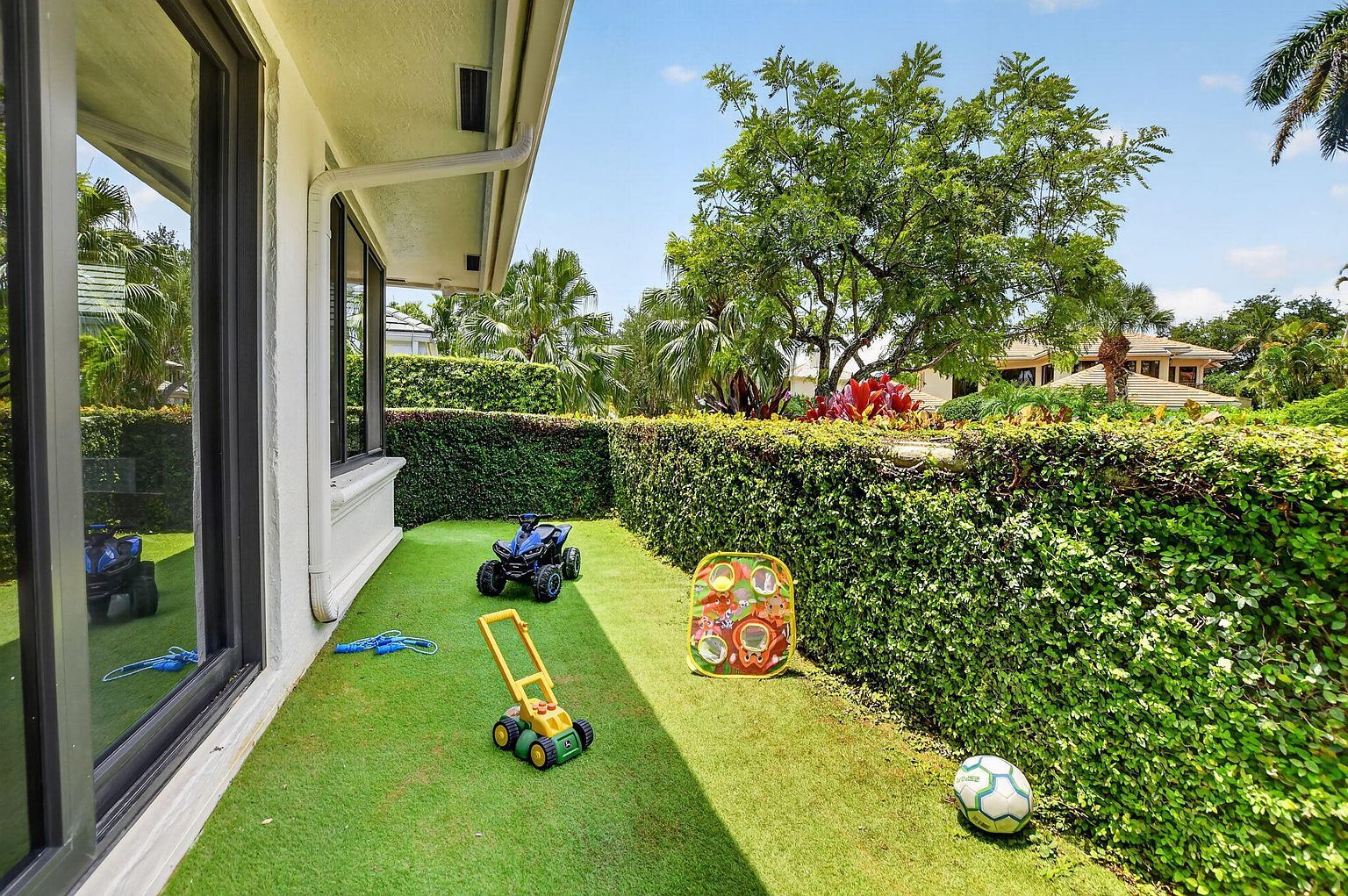 Private fenced turf play area off the kitchen, with kids' toys