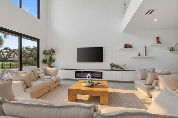 Great room seating area with a wood coffee table, wall-mounted TV and linear fireplace