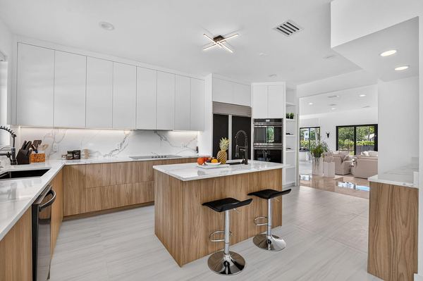 Kitchen island with bar stools, white upper cabinets and the open floor plan beyond