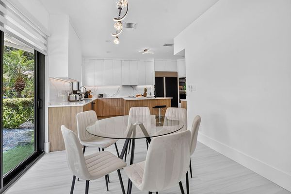 Breakfast area with a glass table, white chairs and a modern pendant light