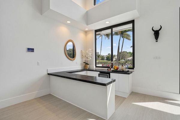 Wet bar with a black counter, a round mirror and a window toward the pool