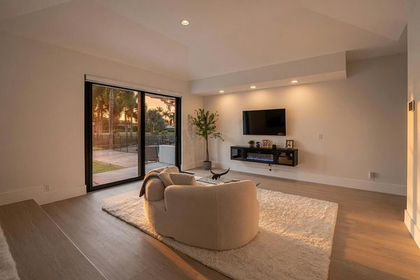 Primary bedroom sitting area with a curved sofa and wall-mounted TV, warm sunset light