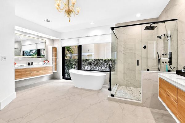 Primary bath with a freestanding tub, a glass shower and floating wood vanities