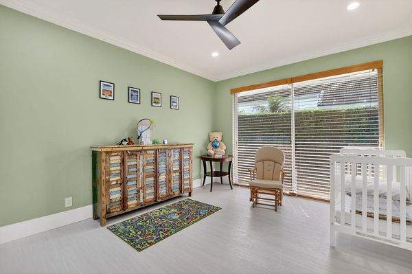 Bedroom set up as a nursery, with sage-green walls, a crib and sliding glass doors