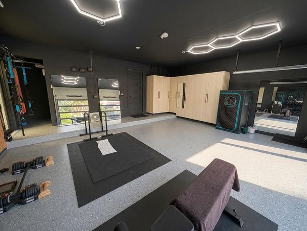 Climate-controlled garage gym with rubber flooring, storage cabinets and hexagon lighting