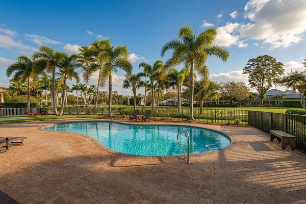 Pool and paver deck with a safety fence, with palm-lined golf course views
