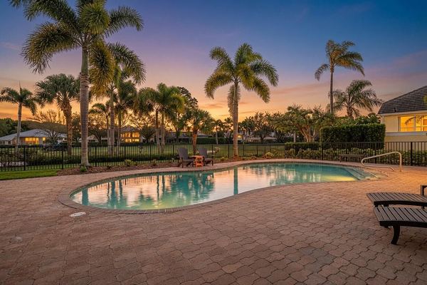 Pool at sunset with palms and lounge seating on the paver deck